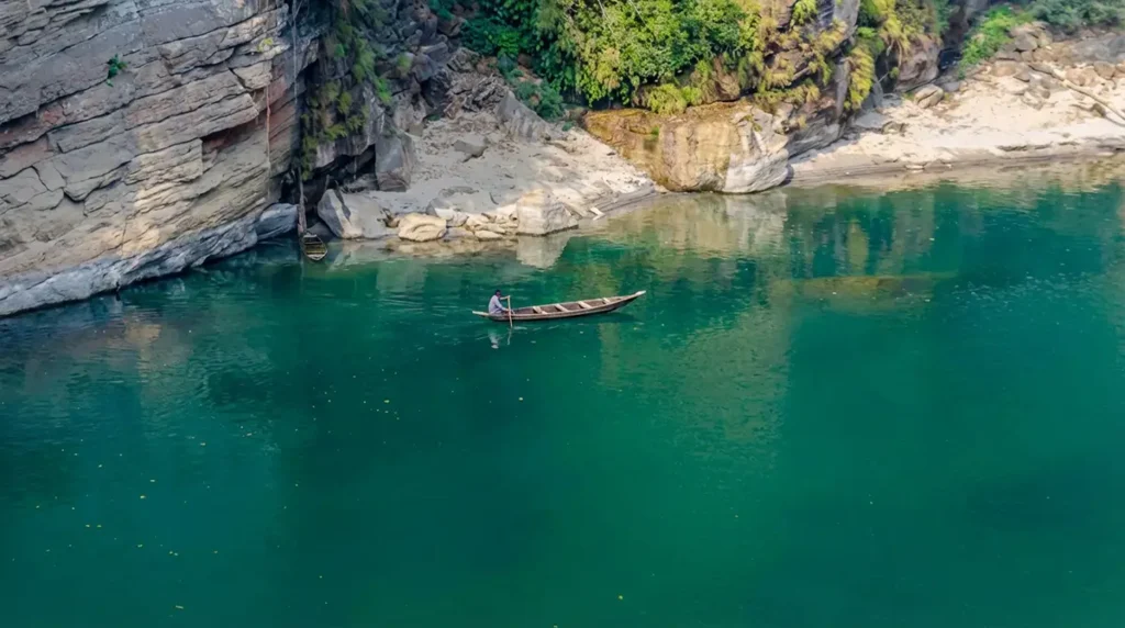 Bateau traditionnel semblant léviter sur l'eau transparente de la rivière Umngot à Dawki, Meghalaya, avec fond visible à travers l'eau