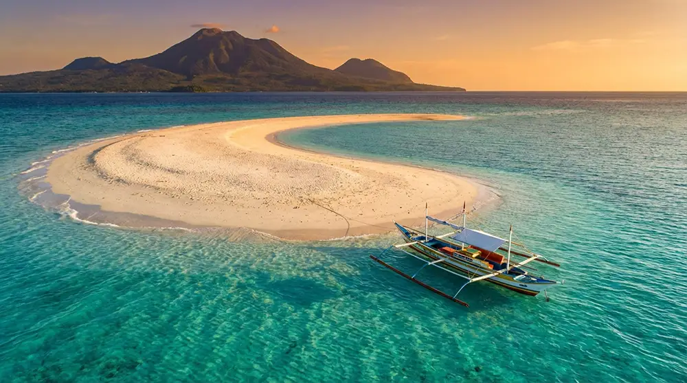 Banc de sable blanc de White Island entouré d'eaux turquoise avec les volcans de Camiguin en arrière-plan
