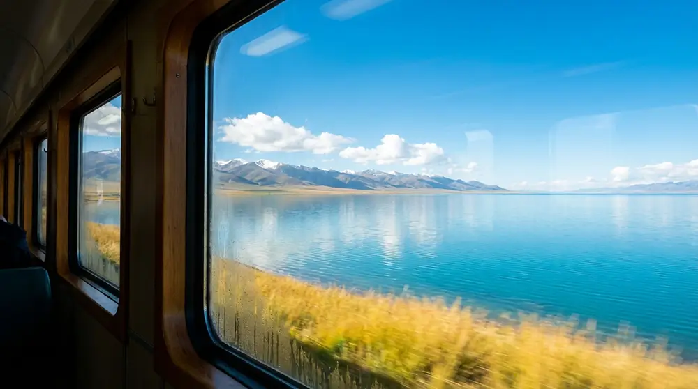 Vue depuis la fenêtre du Lhassa Express sur le lac Qinghai aux eaux turquoise entouré de prairies dorées